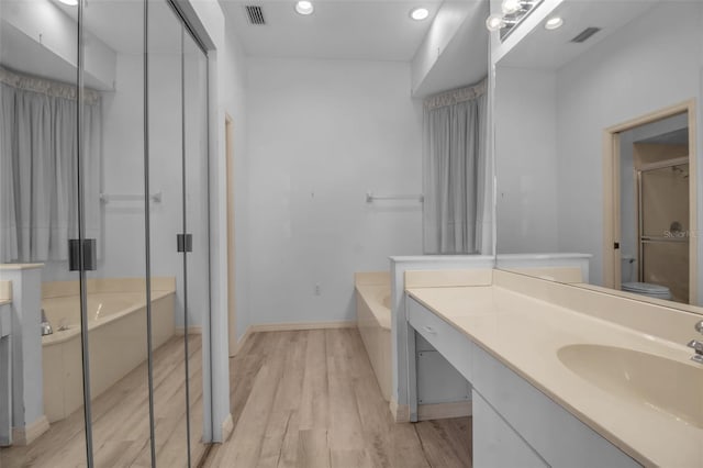 full bathroom featuring wood-type flooring, toilet, vanity, and separate shower and tub