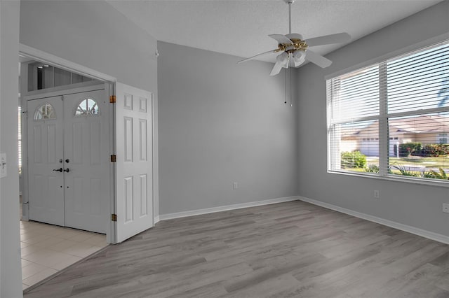 foyer with a textured ceiling, ceiling fan, and light hardwood / wood-style flooring