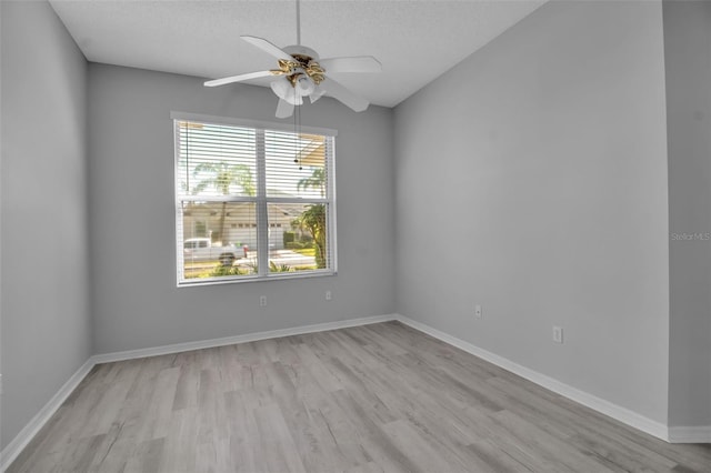 spare room with light wood-type flooring, lofted ceiling, ceiling fan, and a textured ceiling