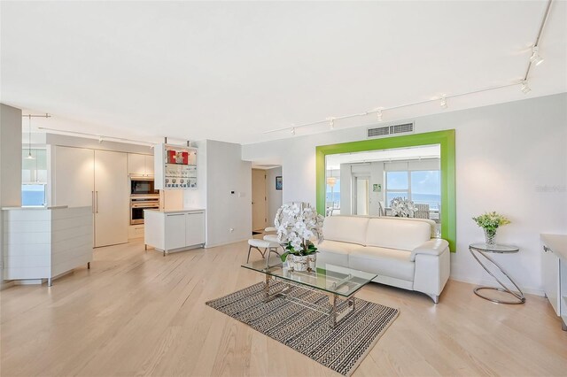 living room featuring visible vents, light wood-style floors, and rail lighting