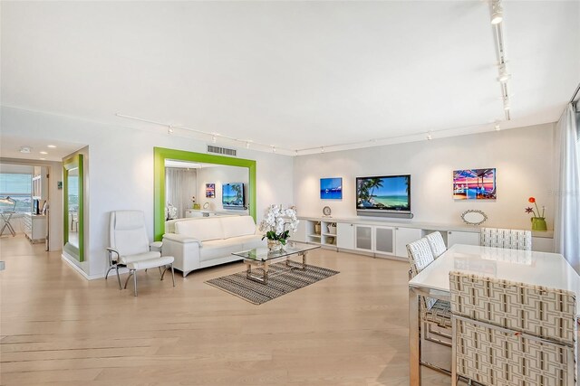 living room featuring rail lighting, wood finished floors, and visible vents