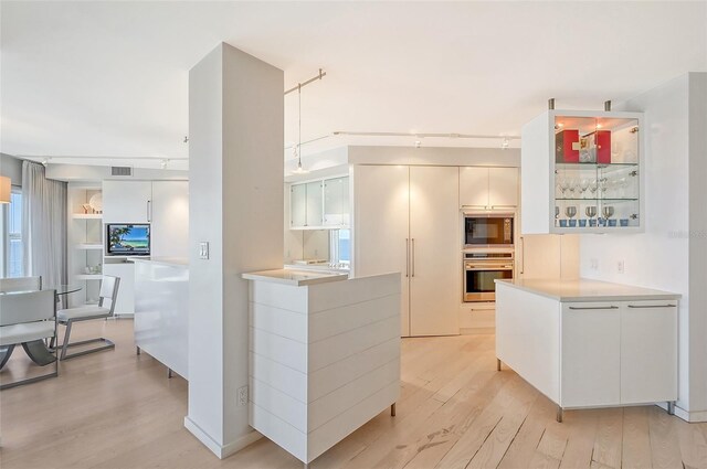 kitchen with visible vents, light wood finished floors, oven, light countertops, and black microwave