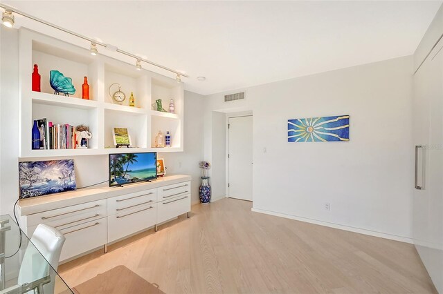 sitting room featuring light wood finished floors, visible vents, track lighting, and built in features