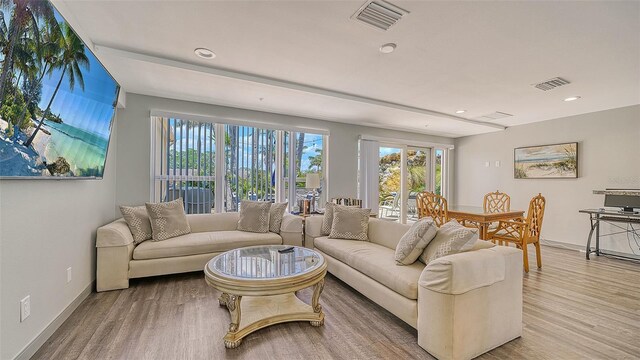 living room with recessed lighting, visible vents, baseboards, and wood finished floors