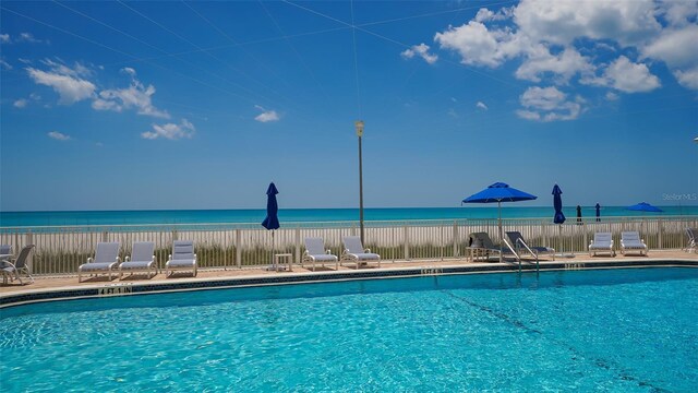 community pool featuring a water view and fence