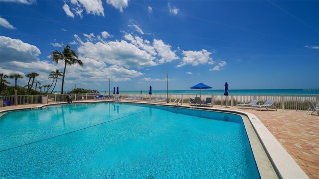 community pool with a patio area and fence