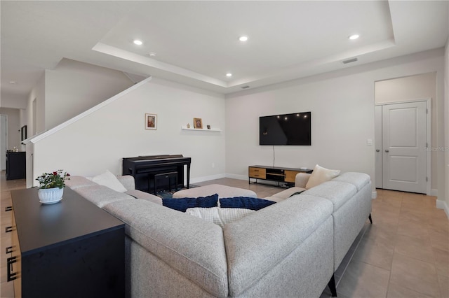 living room featuring a fireplace, a raised ceiling, and light tile patterned flooring