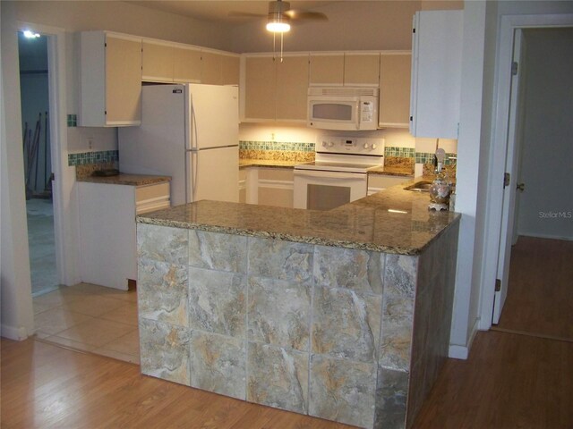 kitchen with white appliances, kitchen peninsula, sink, hardwood / wood-style flooring, and ceiling fan