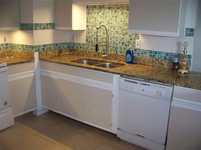 kitchen with dark stone countertops, white dishwasher, white cabinetry, and sink