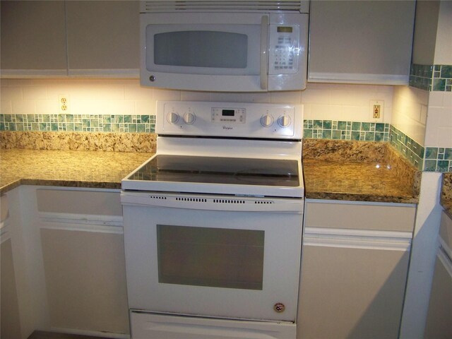 kitchen featuring stone countertops, white appliances, and decorative backsplash