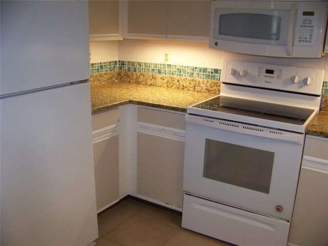 kitchen featuring light tile patterned floors, white appliances, light stone counters, white cabinetry, and tasteful backsplash