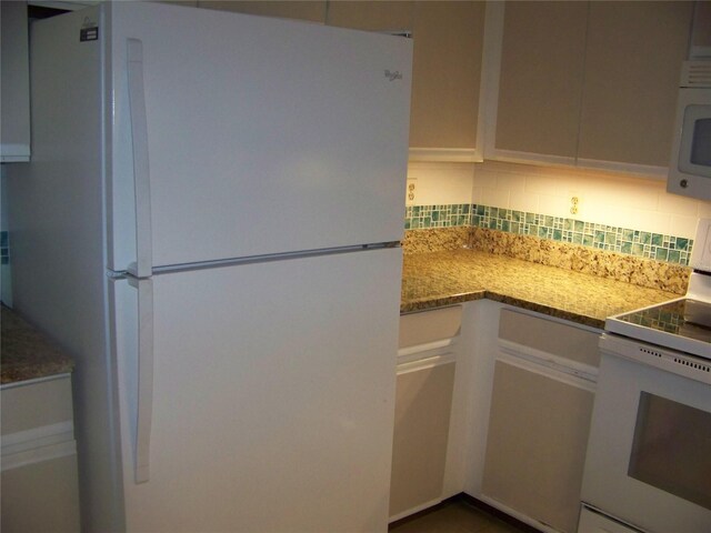 kitchen featuring backsplash, light stone countertops, and white appliances