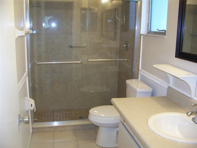 bathroom featuring vanity, toilet, tile patterned flooring, and a shower with door