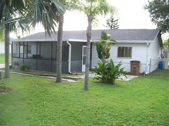 back of property with a sunroom and a lawn