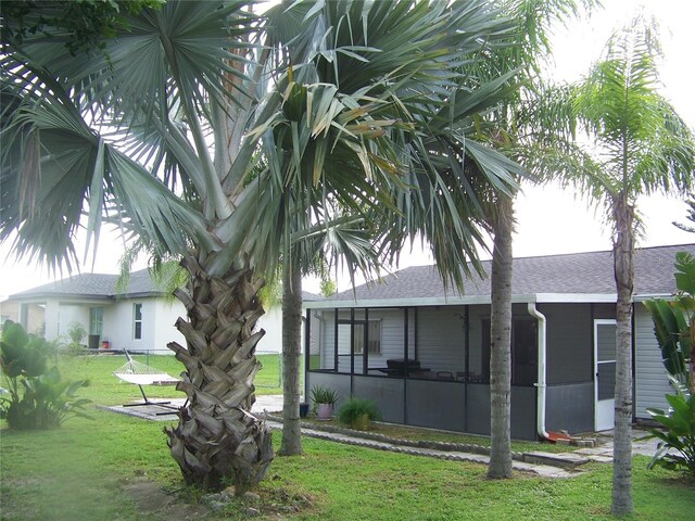 back of property featuring a lawn and a sunroom