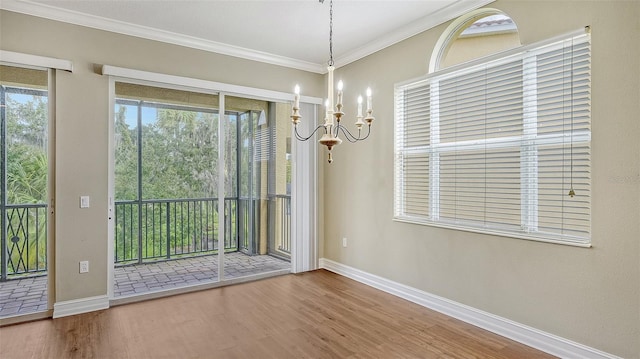 interior space with crown molding, wood-type flooring, an inviting chandelier, and a healthy amount of sunlight