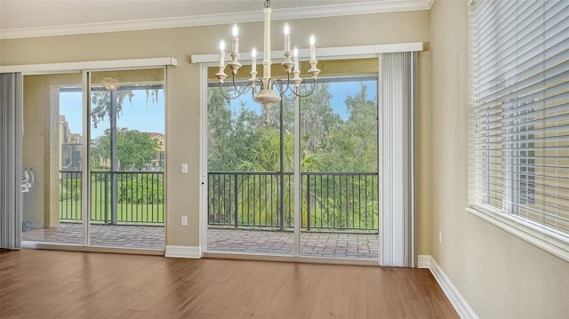 unfurnished dining area featuring ornamental molding, wood-type flooring, and a notable chandelier