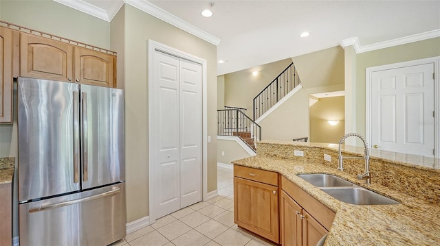 kitchen featuring stainless steel refrigerator, ornamental molding, light tile patterned floors, sink, and light stone countertops