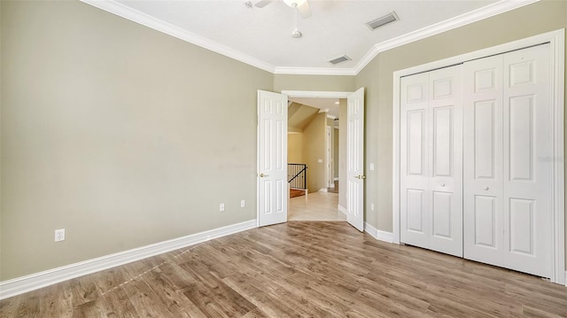 unfurnished bedroom with light wood-type flooring, crown molding, ceiling fan, and a closet