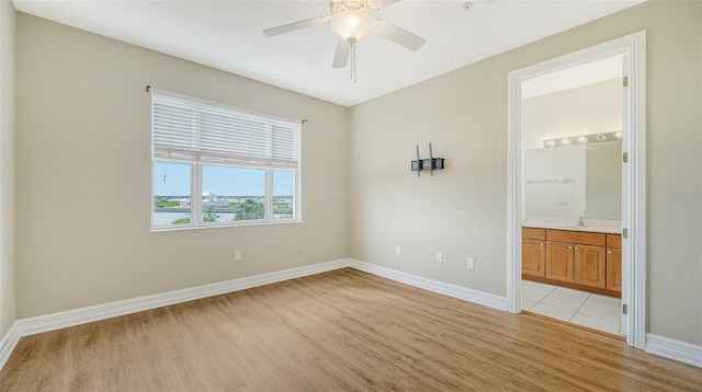 unfurnished bedroom with light hardwood / wood-style flooring, connected bathroom, sink, and ceiling fan