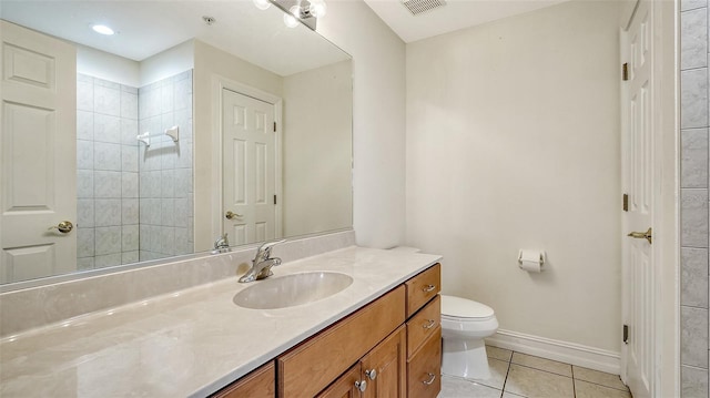 bathroom with vanity, toilet, tiled shower, and tile patterned flooring