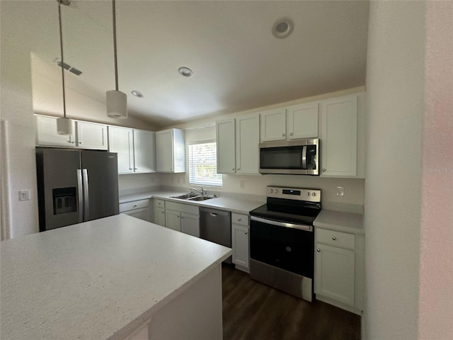 kitchen with pendant lighting, stainless steel appliances, sink, lofted ceiling, and white cabinets