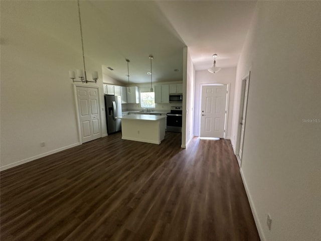 kitchen featuring pendant lighting, stainless steel appliances, a kitchen island, vaulted ceiling, and white cabinets