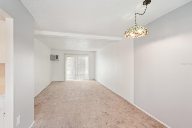 carpeted empty room with beam ceiling and an AC wall unit