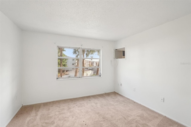 spare room featuring light colored carpet, a textured ceiling, and a wall unit AC