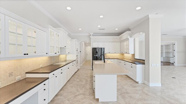 kitchen featuring white cabinets, tasteful backsplash, a kitchen island with sink, and stainless steel refrigerator with ice dispenser