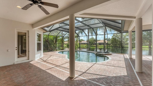 view of swimming pool featuring a patio area, a water view, glass enclosure, and ceiling fan