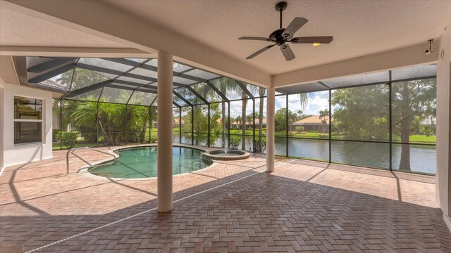 view of swimming pool featuring an in ground hot tub, a water view, a lanai, a patio area, and ceiling fan