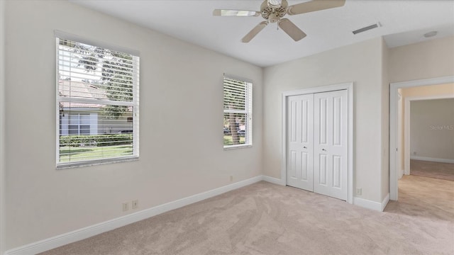 unfurnished bedroom featuring a closet, ceiling fan, and light colored carpet