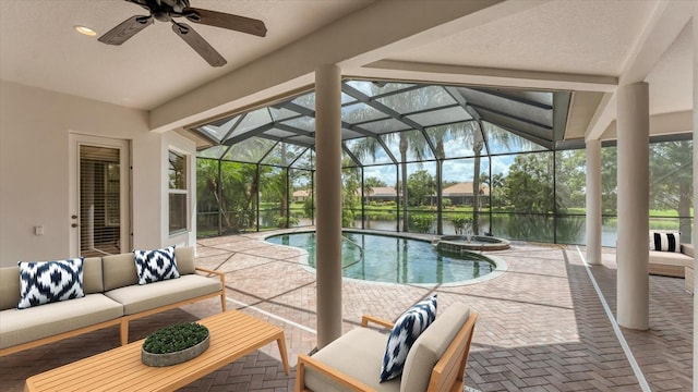 view of swimming pool featuring a patio, an outdoor living space, a water view, glass enclosure, and ceiling fan