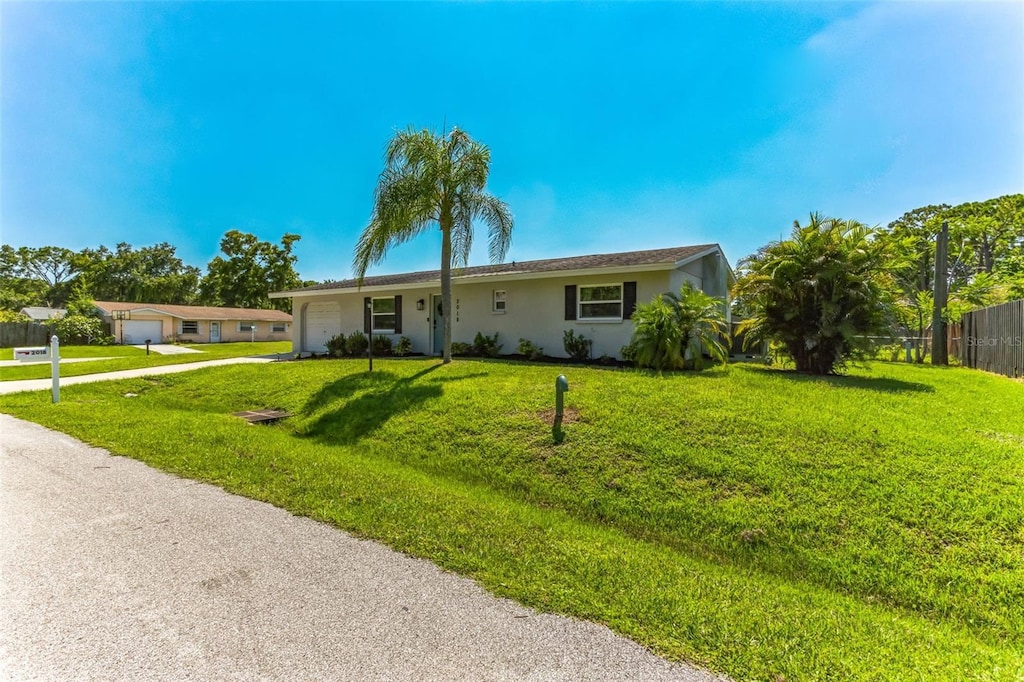 ranch-style home featuring an attached garage, a front yard, and fence