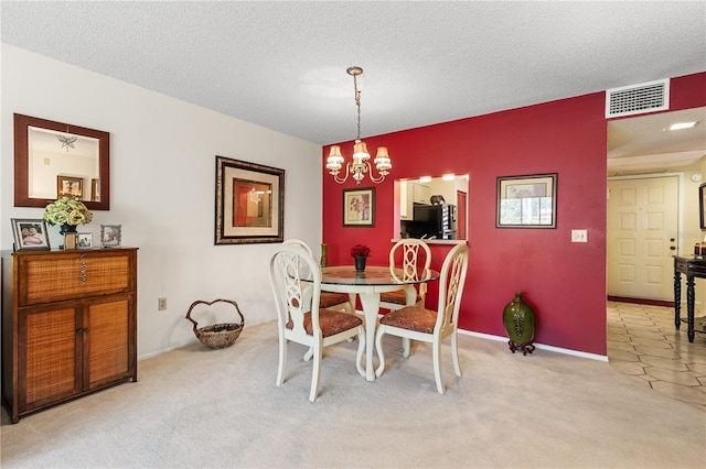 dining room with a textured ceiling, light colored carpet, and a chandelier