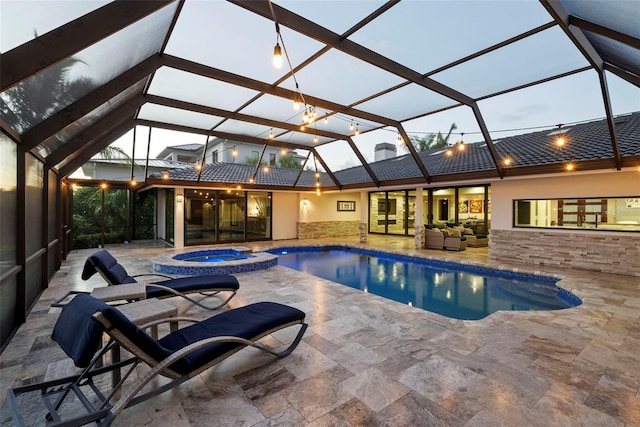 pool at dusk featuring an in ground hot tub, a lanai, and a patio area