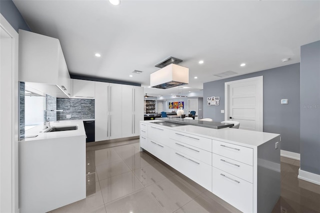 kitchen featuring decorative backsplash, white cabinetry, a kitchen island, and sink