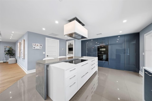 kitchen featuring black appliances, light hardwood / wood-style floors, a kitchen island, and white cabinets