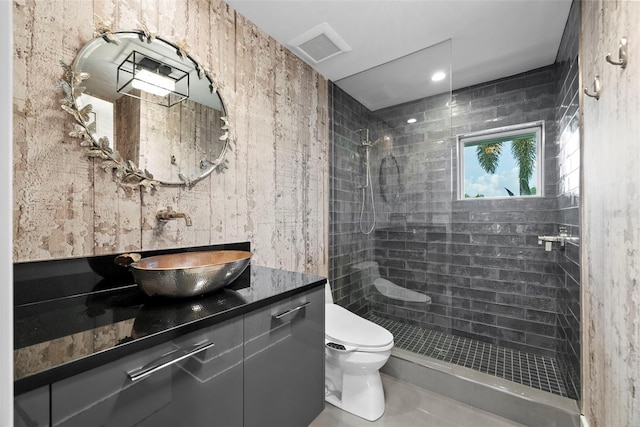 bathroom with a tile shower, vanity, and toilet