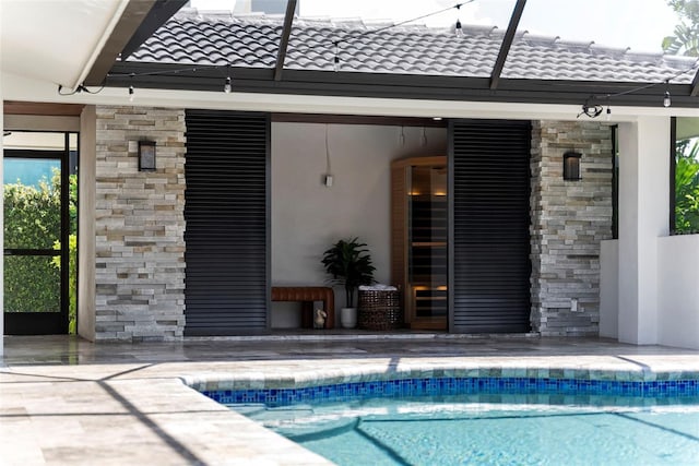 back of property featuring glass enclosure and a patio