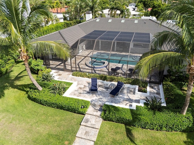 view of pool with glass enclosure, a lawn, and a patio area