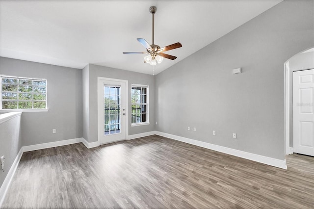 spare room featuring a healthy amount of sunlight, ceiling fan, hardwood / wood-style floors, and vaulted ceiling