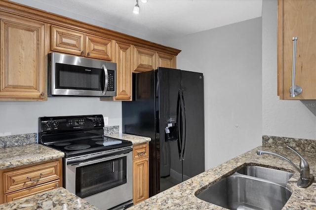 kitchen featuring light stone countertops, stainless steel appliances, and sink