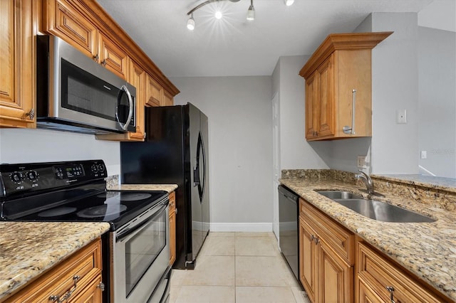 kitchen featuring appliances with stainless steel finishes, light tile patterned floors, light stone countertops, and sink