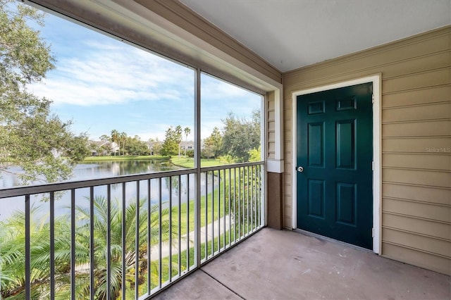 view of exterior entry featuring a water view and a balcony