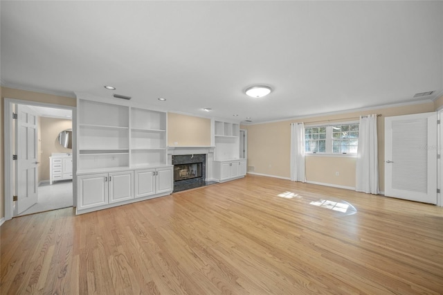 unfurnished living room with ornamental molding, a high end fireplace, light hardwood / wood-style floors, and built in features