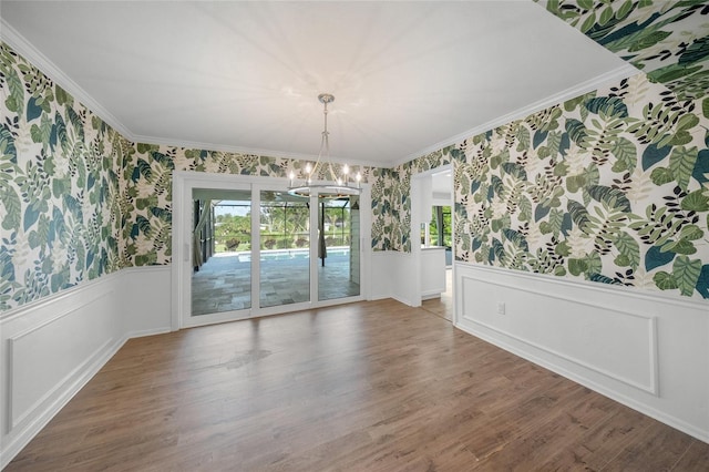 unfurnished dining area with a notable chandelier, hardwood / wood-style floors, and crown molding