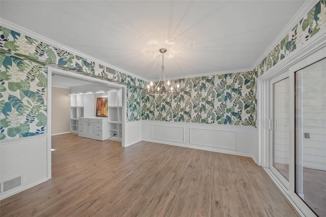 unfurnished dining area with crown molding, an inviting chandelier, and hardwood / wood-style flooring