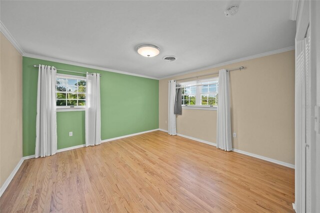 unfurnished room featuring light hardwood / wood-style flooring, crown molding, and a wealth of natural light